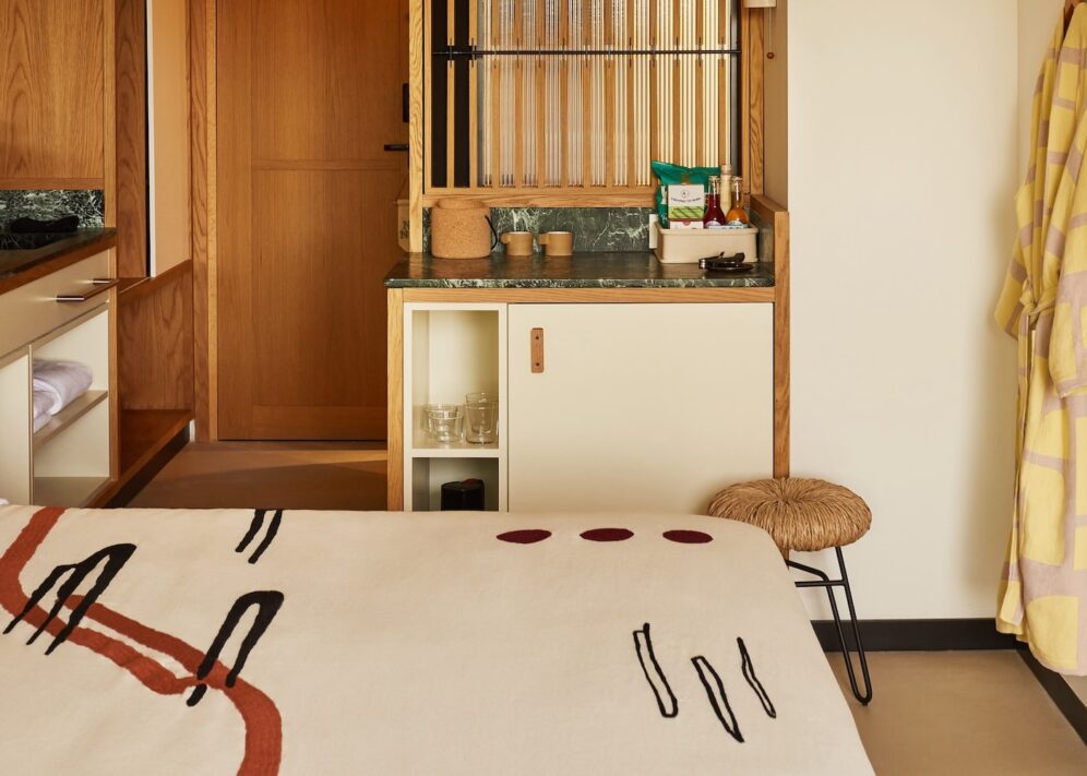A small bedroom with a neatly made bed and a colorful robe.