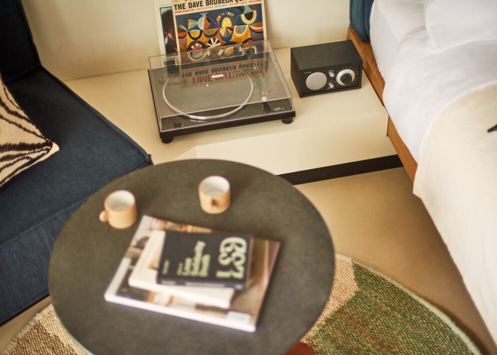 A small table featuring a vintage record player and a magazine, creating a cozy reading and listening space.