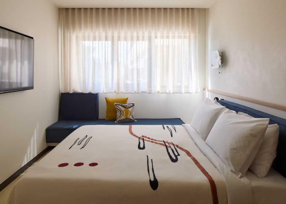 A stylish hotel room showcasing a bed, a television, and a window with sunlight streaming in
