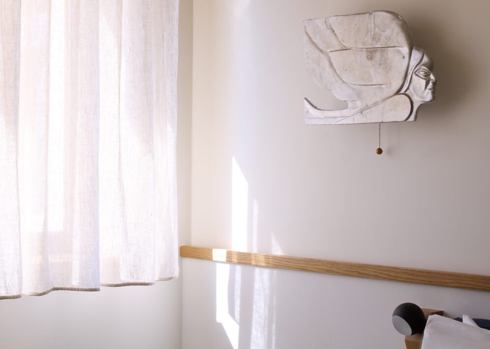 A serene white bed with a soft white pillow, set against a clean white wall.