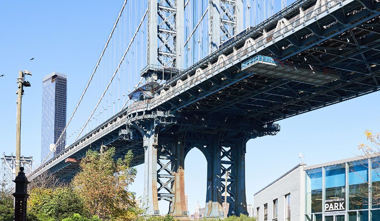 Brooklyn bridge in the daytime and people walking underneath