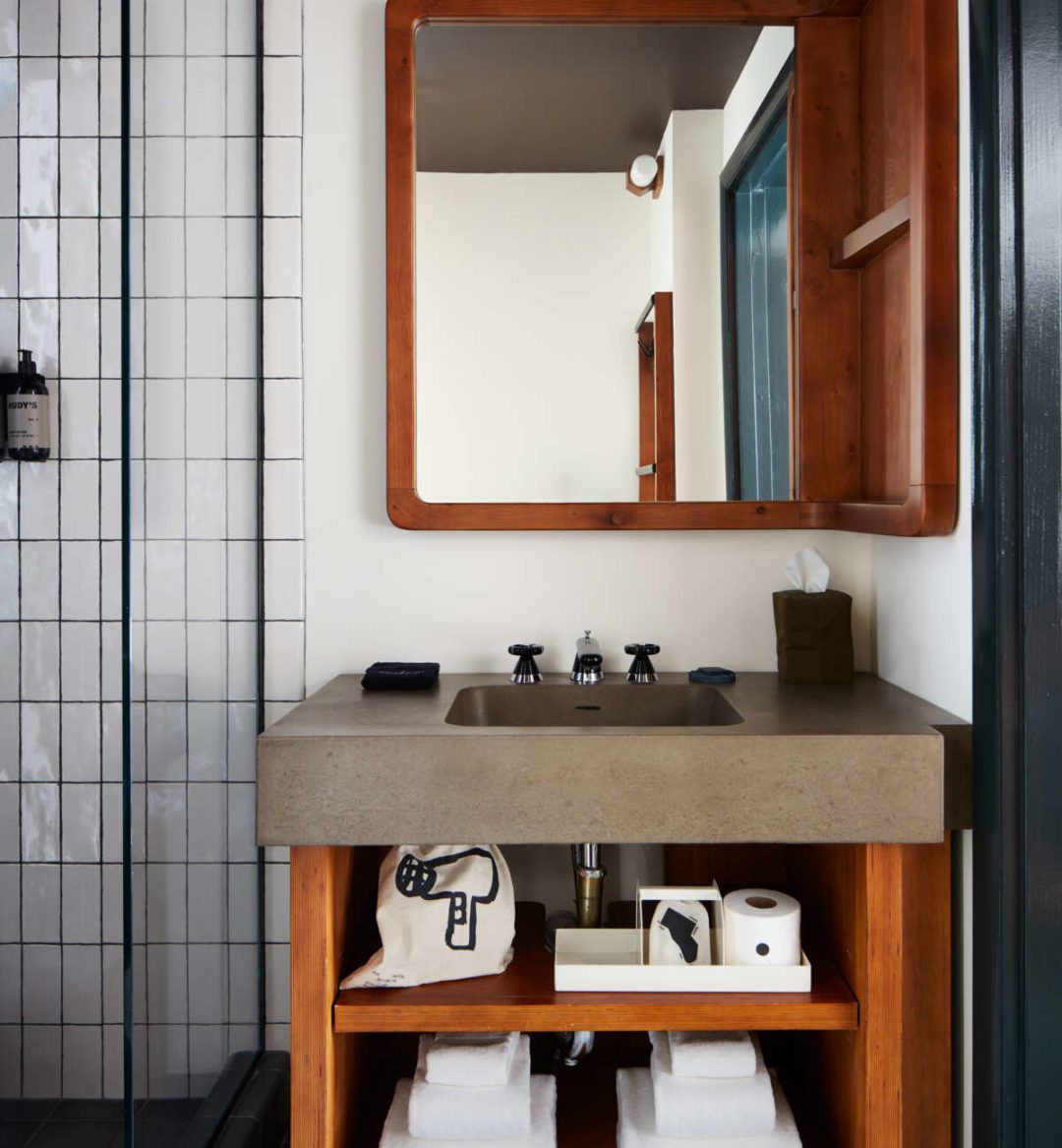 Sleek, modern bathroom with a concrete sink, walk-in shower and a wood detailed mirror