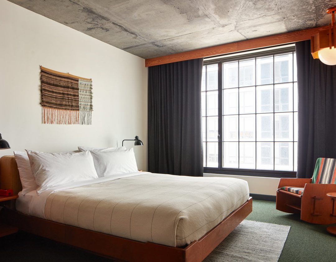 A room with modern styling featuring a striped rocking chair and concrete ceiling