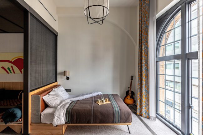 a room at ace hotel kyoto with a bed and a guitar