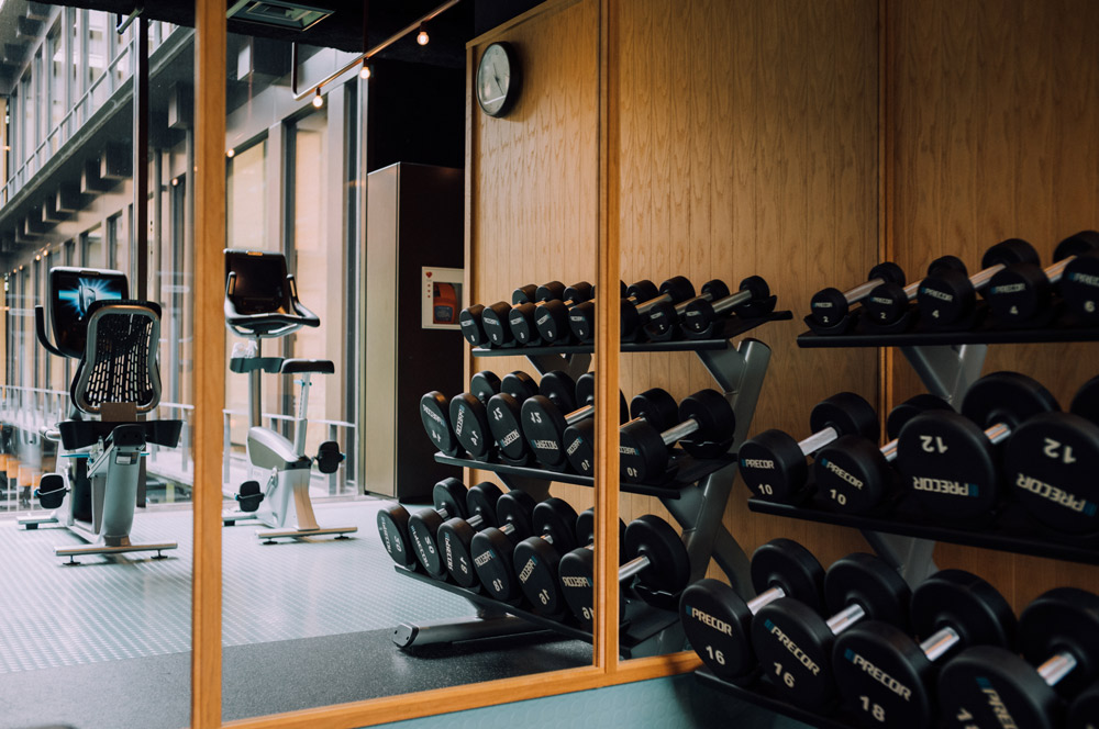 a photo of a gym with equipment that includes free weights and exercise bikes.