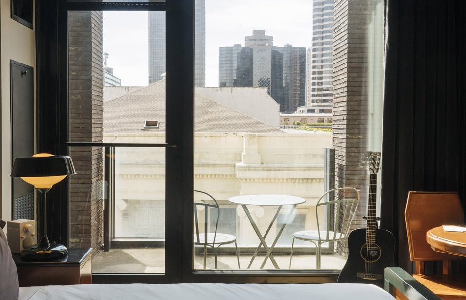 A hotel room patio with seating area and view of the city