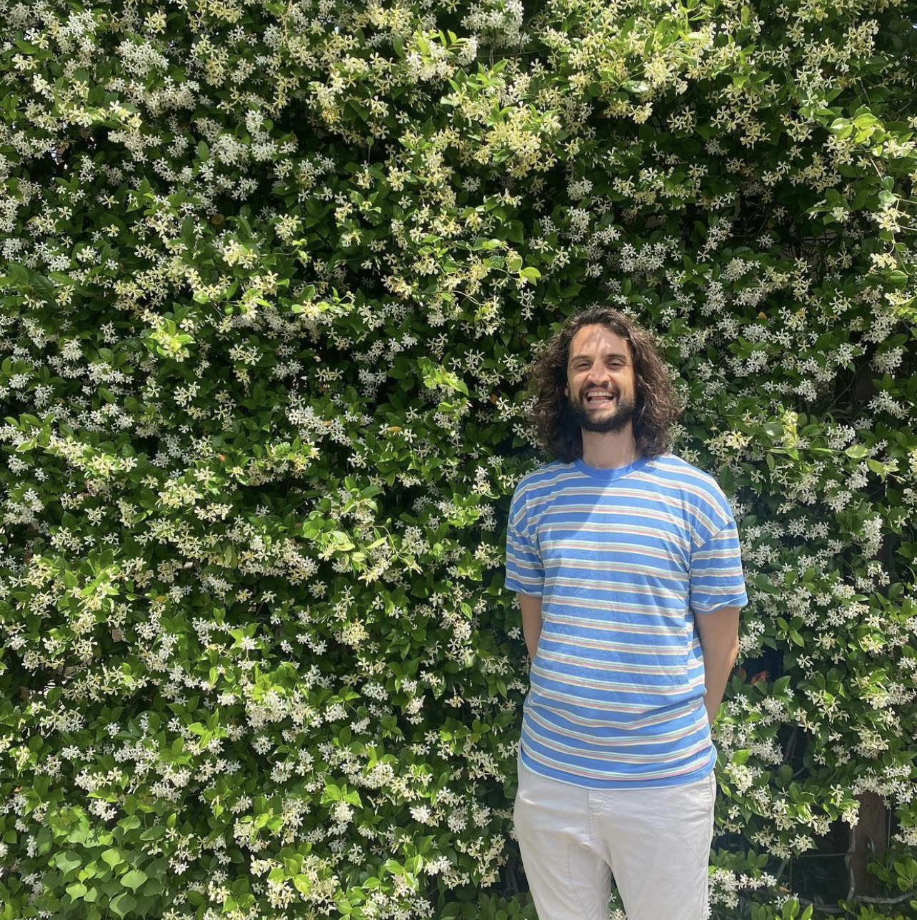 Joshua Starkman in front of wall of flowers