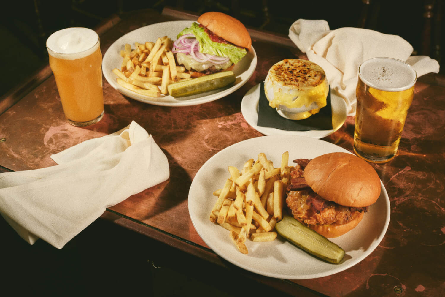 two burger plates and glasses of beer