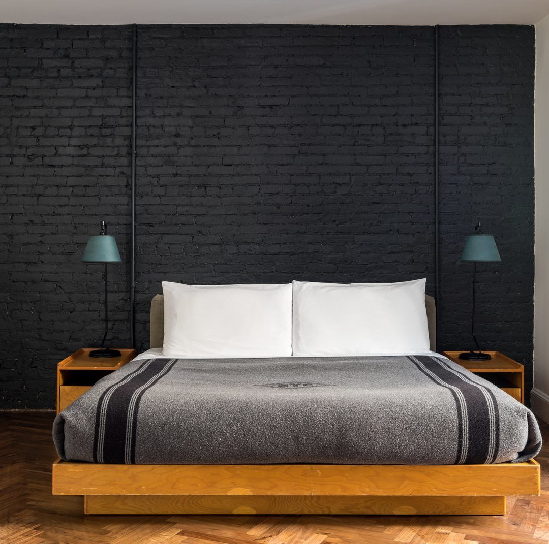 A black exposed brick wall is juxtaposed with bight, polished wooden flooring