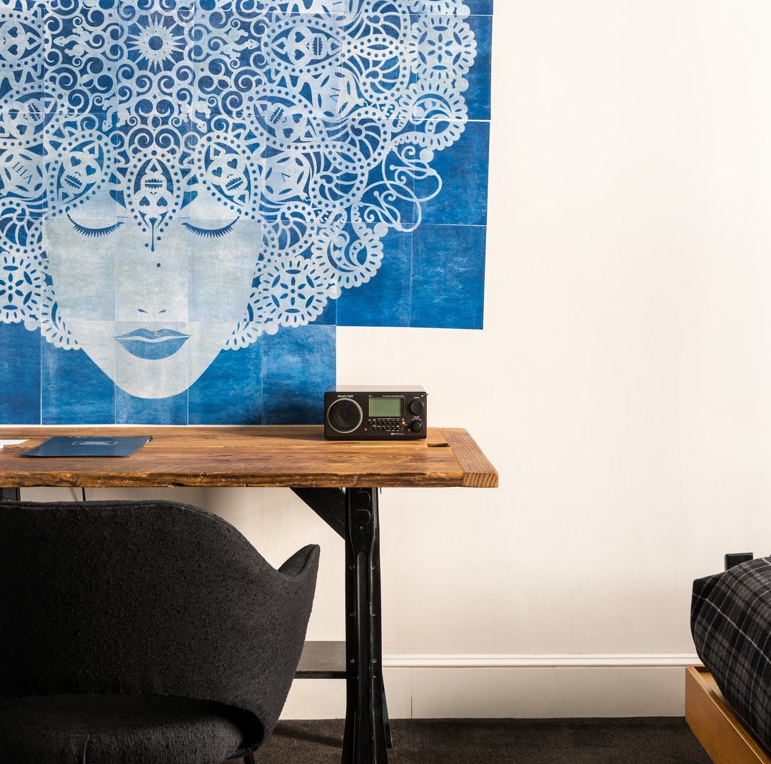 A vintage wooden desk provides space to work and is juxtaposed with the modern vibe of the room