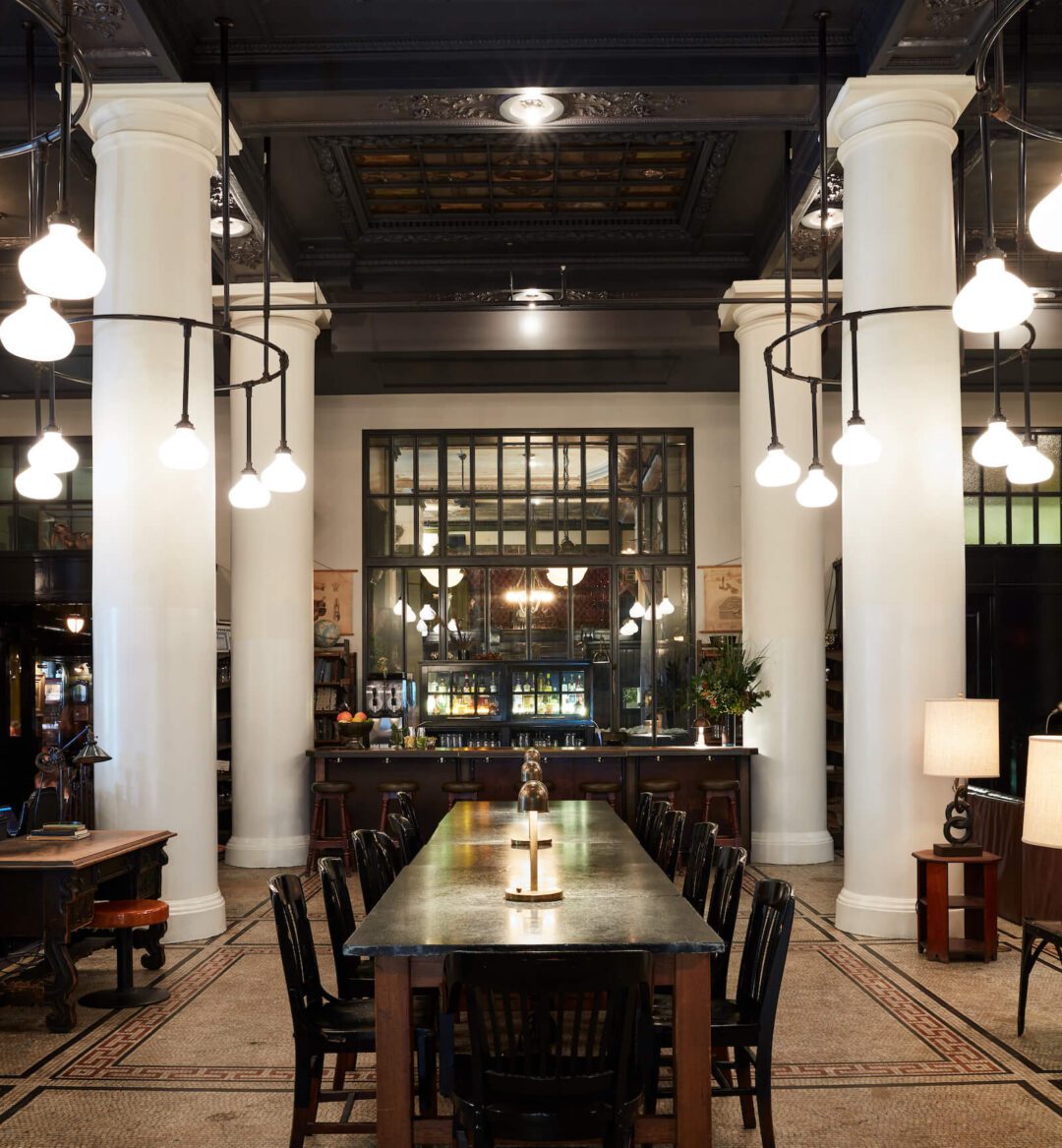 a lobby featuring a long black table and white pillars