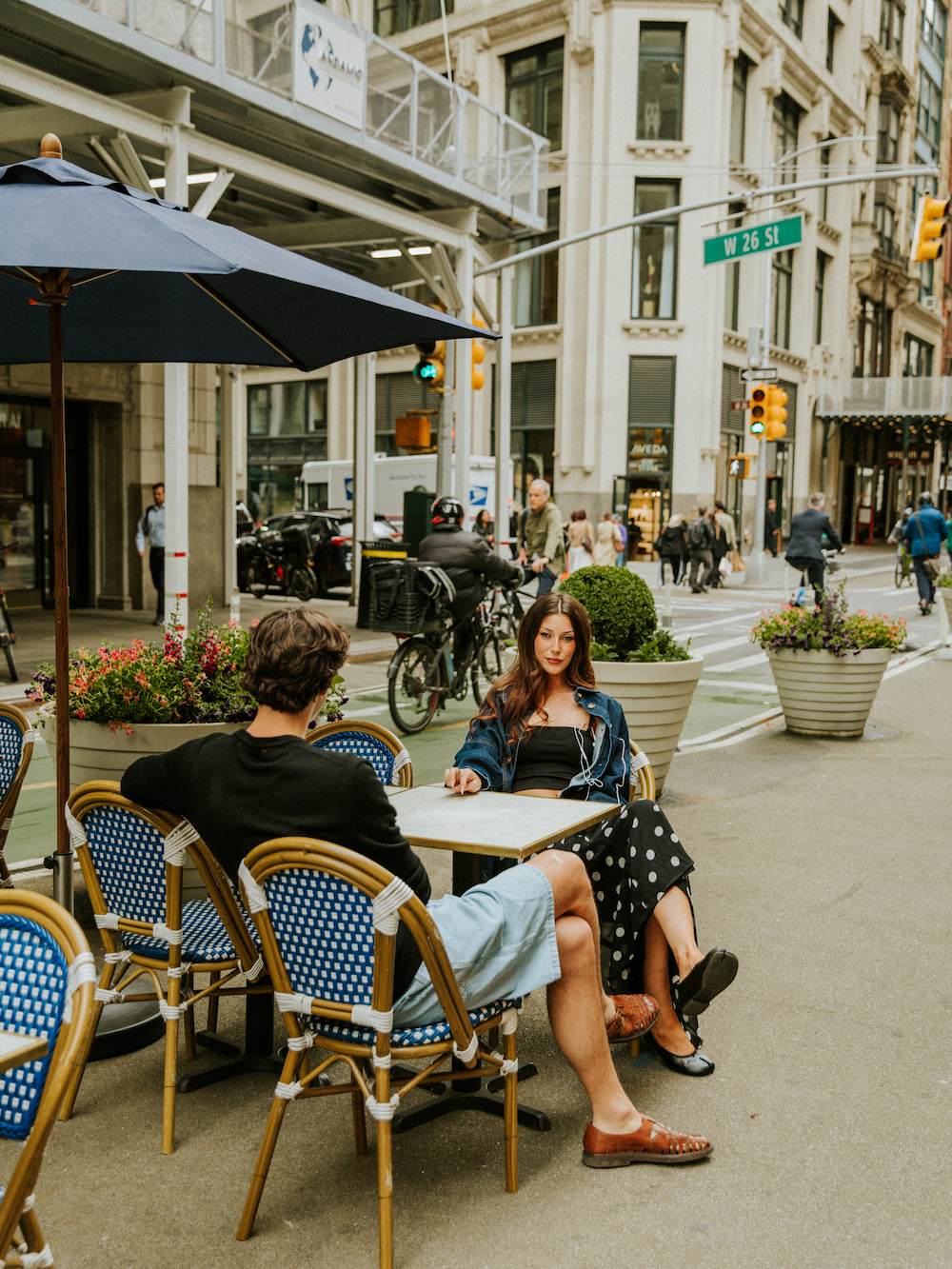 NYC Fashion Week - a couple sitting at a cafe while cars, bike messengers and people pass by