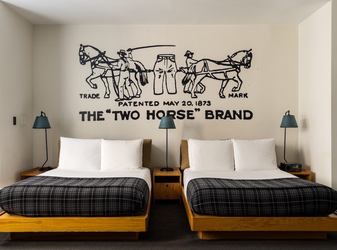 Room with two beds and a hand-painted mural at Ace Hotel New York