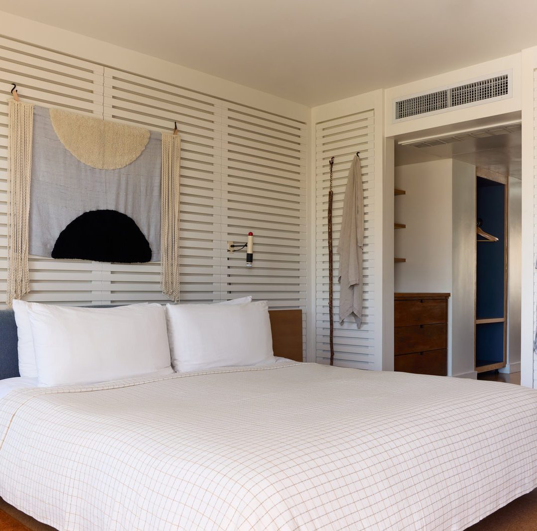 A private bedroom has robes adorning the wall and wall lamps for light into the night