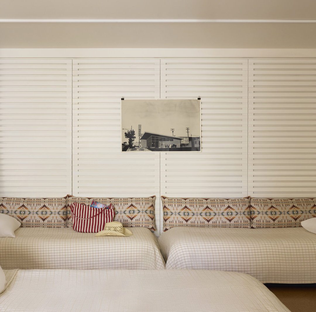 Two twin beds face each other against a wall, and a curtain sits in front of them to provide privacy