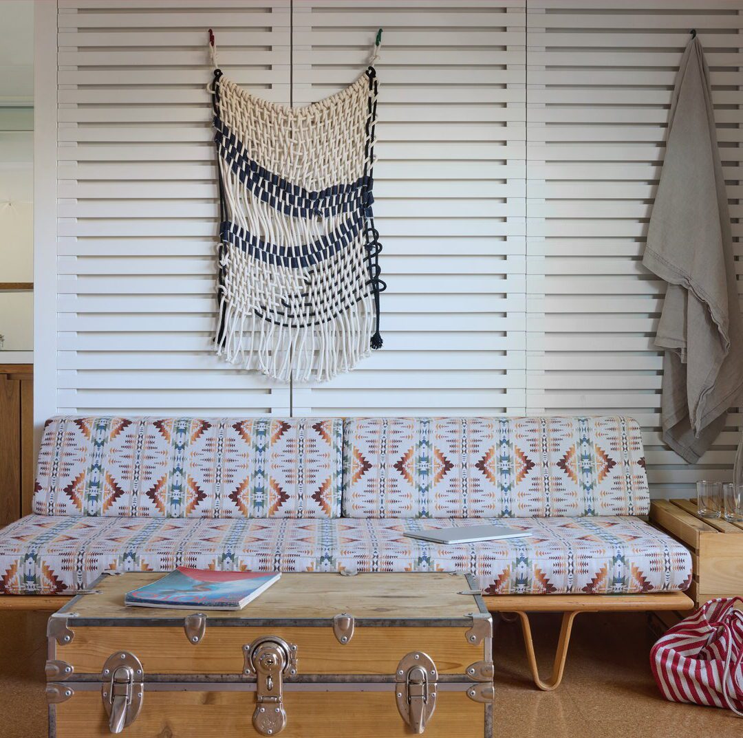 An ornate couch sits close to the floor with a coffee table with magazine for light reading