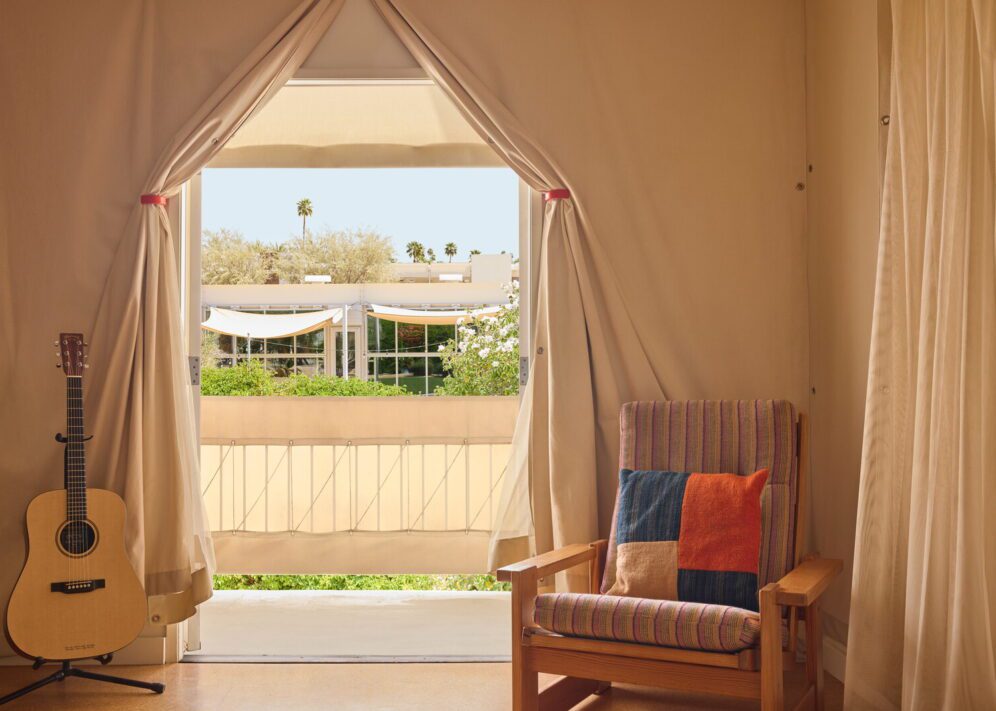 a canopy door is flanked by an acoustic guitar and chair with plaid pillow