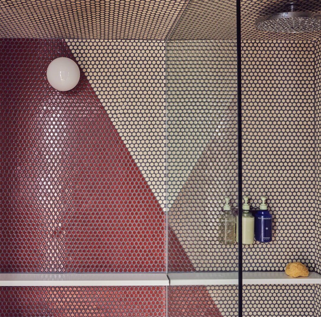 A red and white tiled shower provides a ledge for placing bath products
