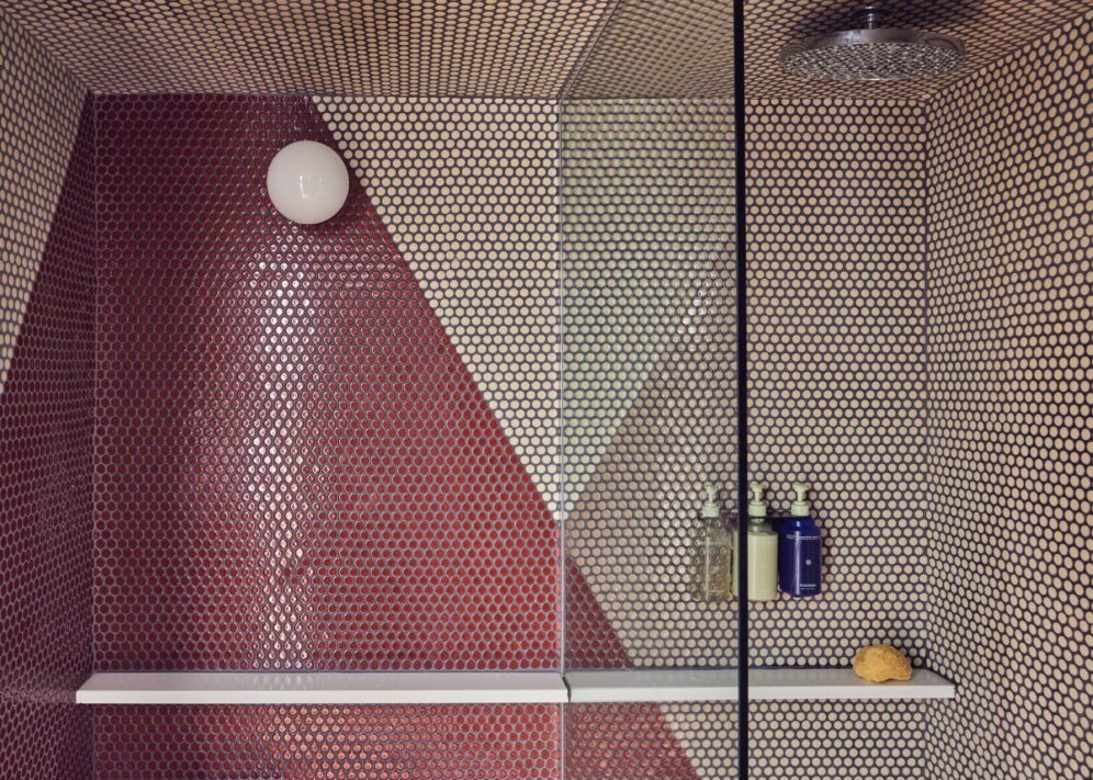 A red and white tiled shower provides a ledge for placing bath products