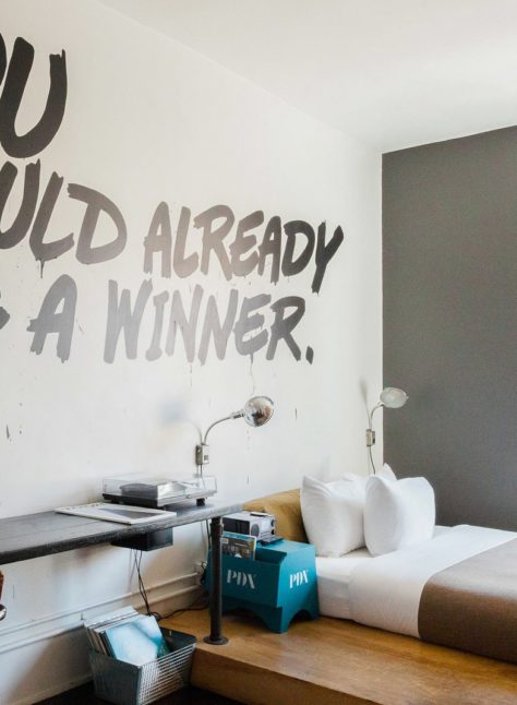 A hotel room with a twin bed and desk