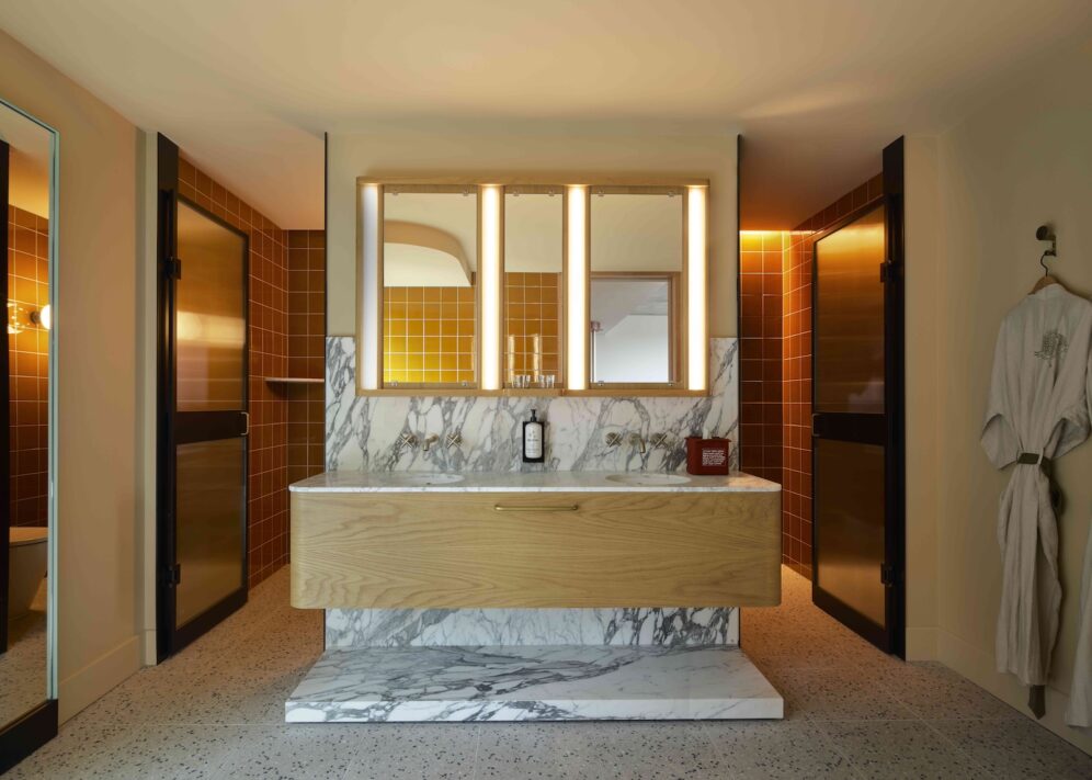 A vanity area sits in the middle of a large bathroom; on either side of the vanity are doors leading to the bathtub