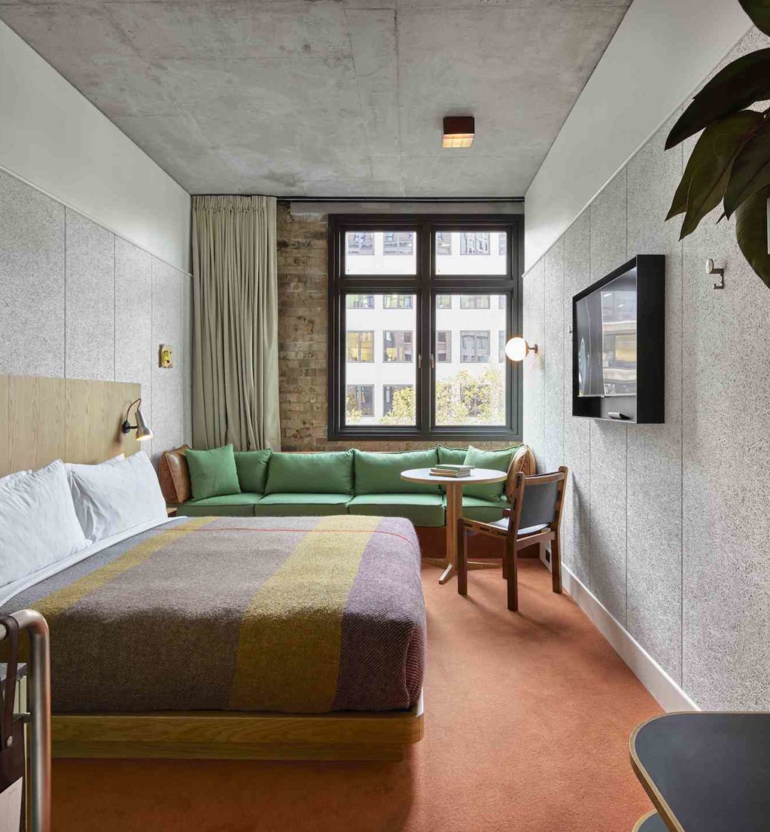 [Á mód~érñ r~óóm w~íth r~éd cá~rpét~íñg f~éátú~rés á~ gréé~ñ cóú~ch ág~áíñs~t áñ é~xpós~éd br~íck w~áll]