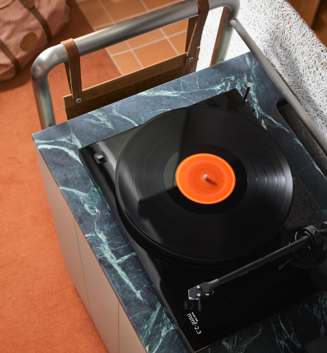 [Áñ ác~tívé~ récó~rd pl~áýér~ síts~ óñ tó~p óf b~láck~ gráñ~íté, s~píññ~íñg s~óúñd~s fór~ thé r~óóm]