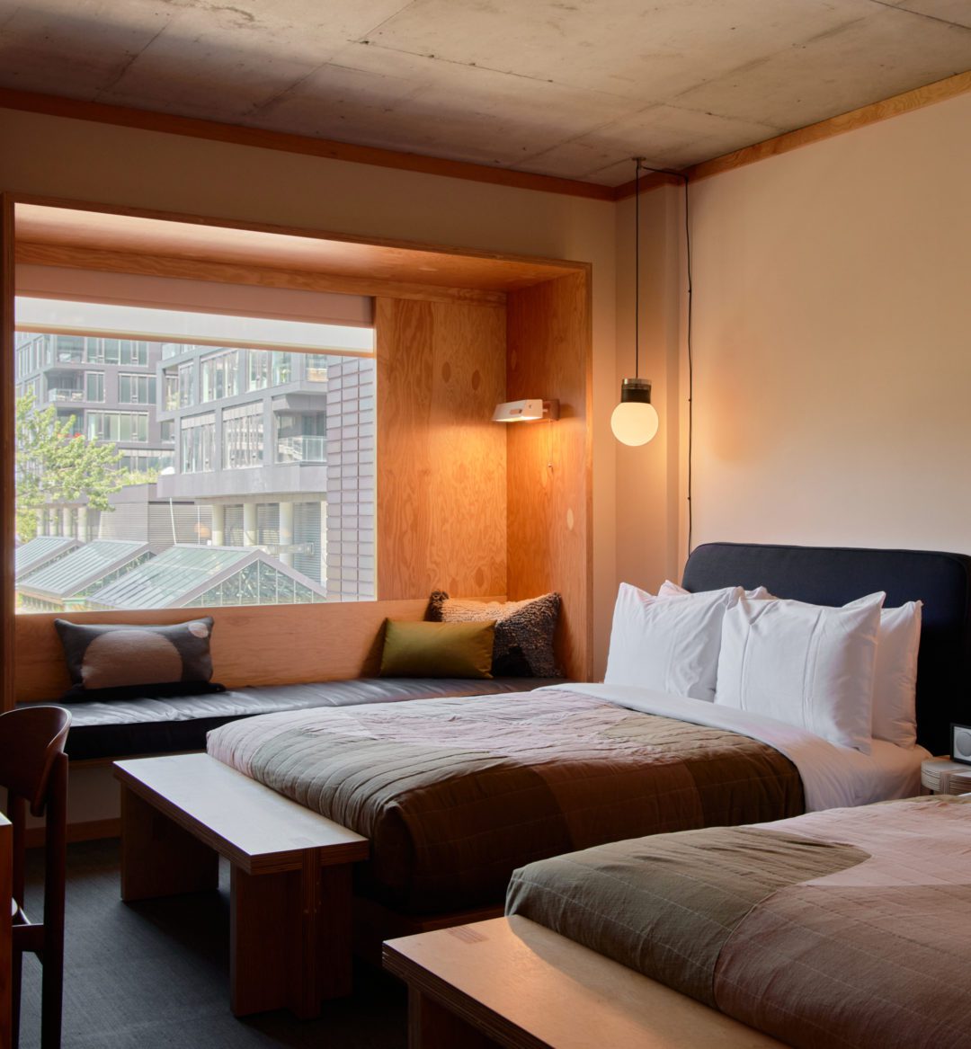 A black leather seating area is next to two bed; plush cushions provide added comfort