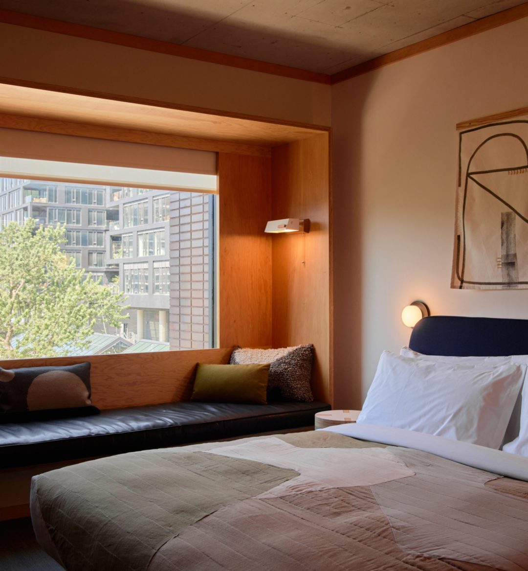 A black leather seating area is next to a bed; plush cushions provide added comfort