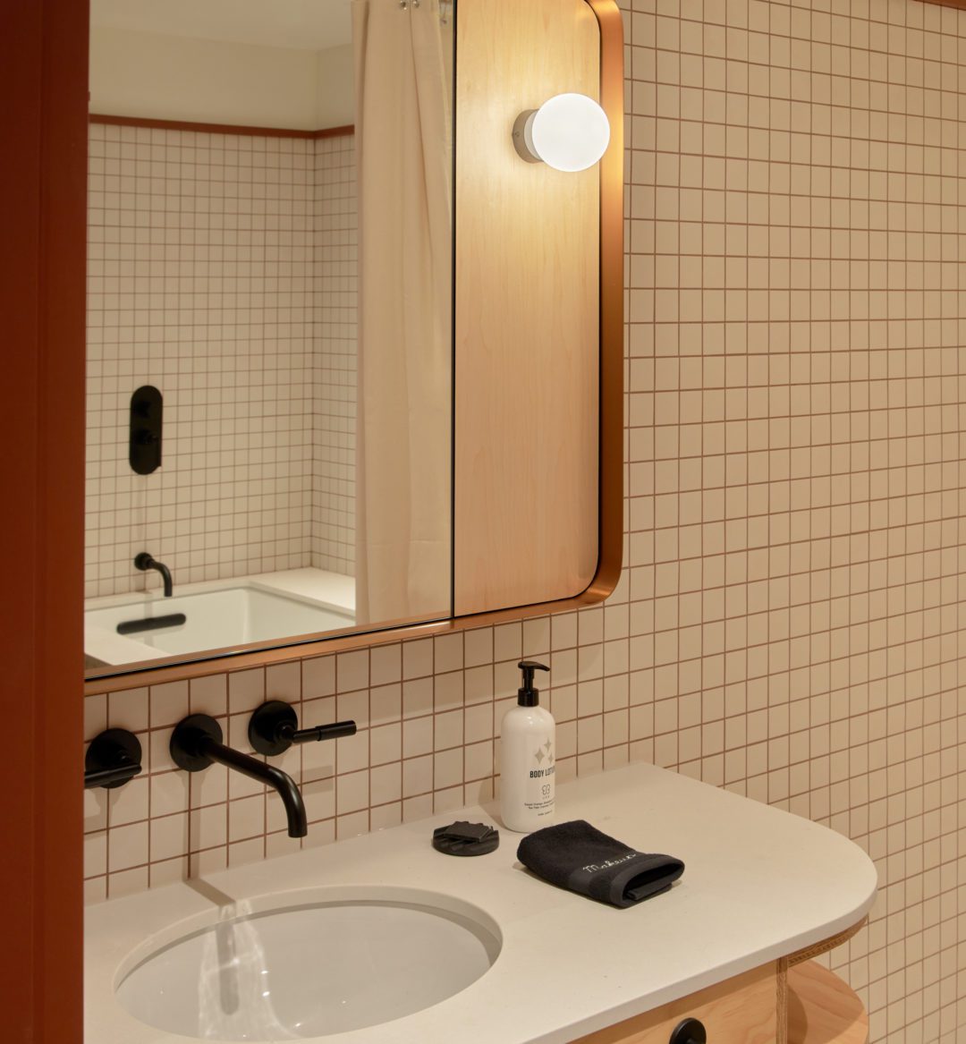 A modern white tiled bathroom features a deep bathtub