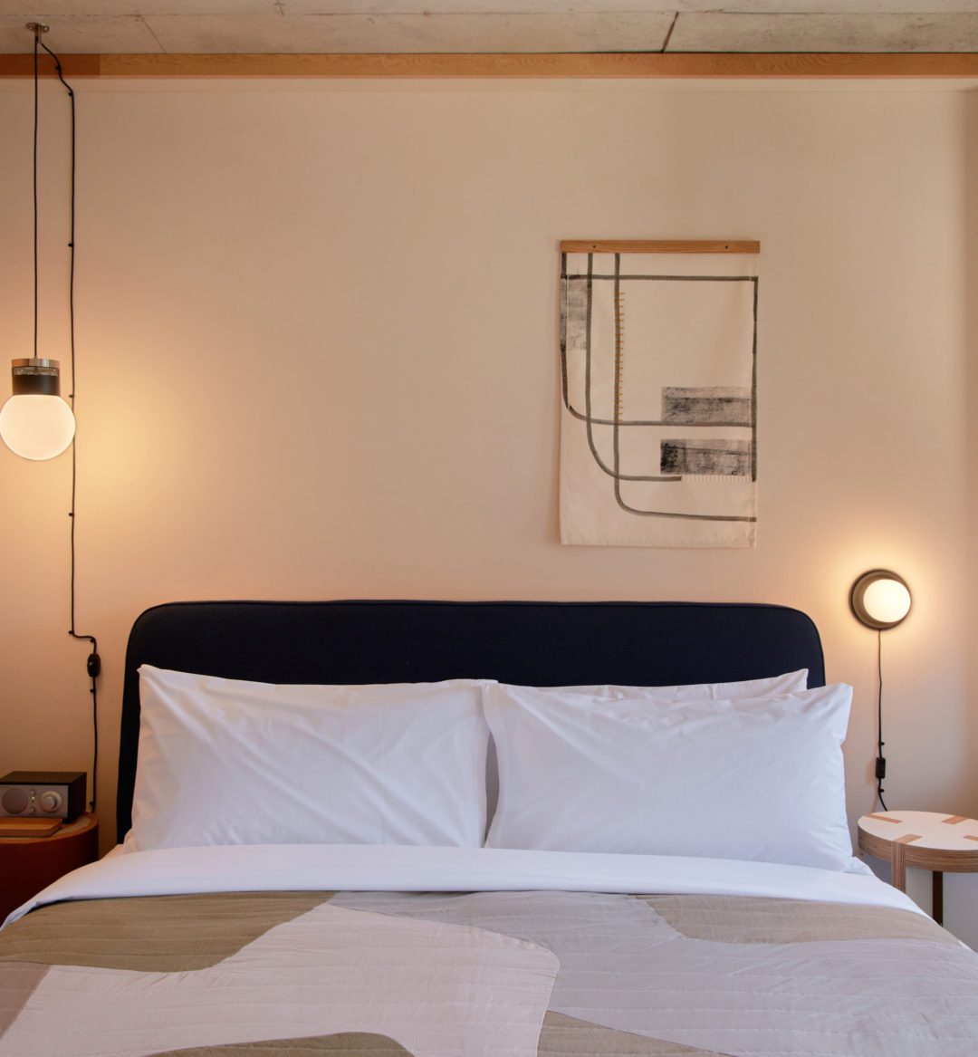A bed sits in between two modern lights, providing a sense of ambience and calm