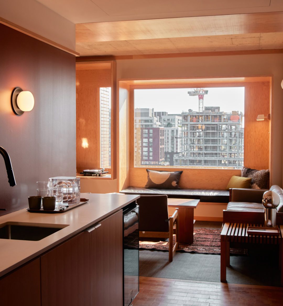 A sink with dishwasher opens up to a large living room with windows and natural light
