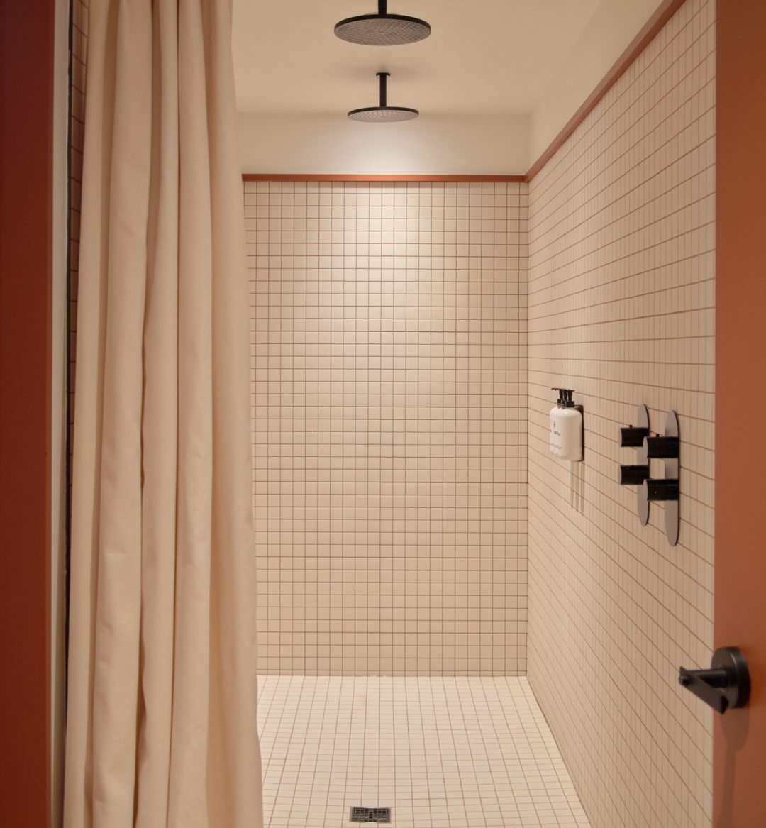 A modern white tiled bathroom features a spacious shower