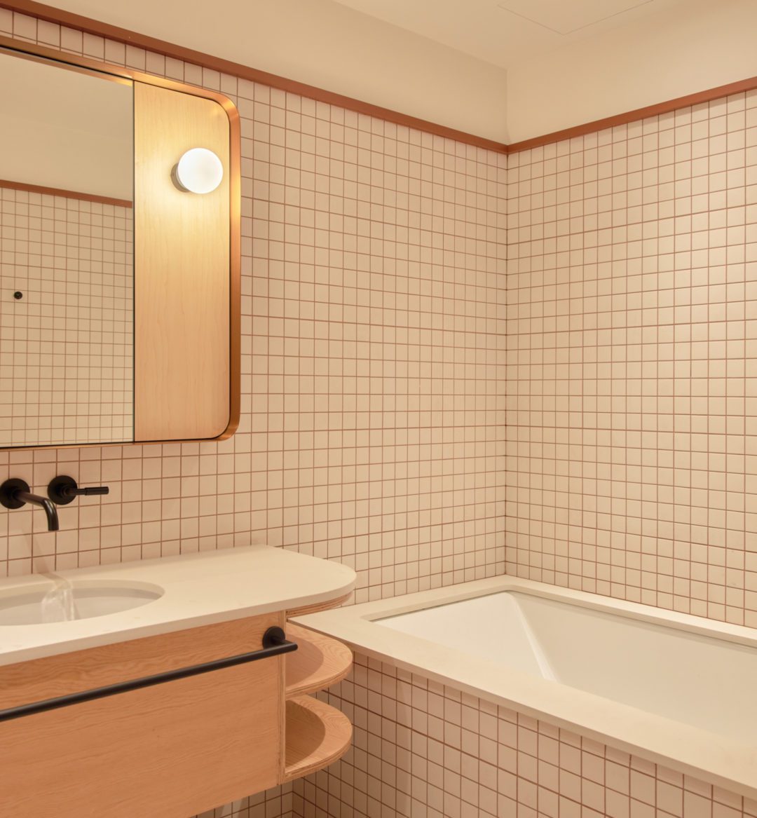 A modern white tiled bathroom features a deep bathtub