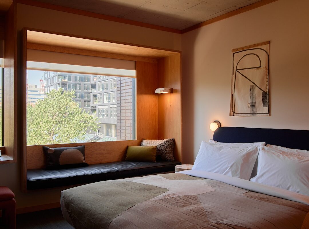 A black leather seating area is next to a bed; plush cushions provide added comfort