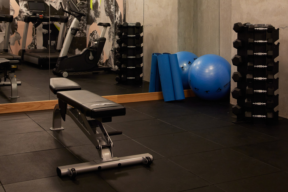 a photo of a gym with equipment that includes various free weights, giant exercise ball, yoga mats and an exercise bench.
