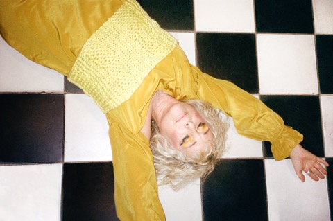 person in yellow laying on checkered tile