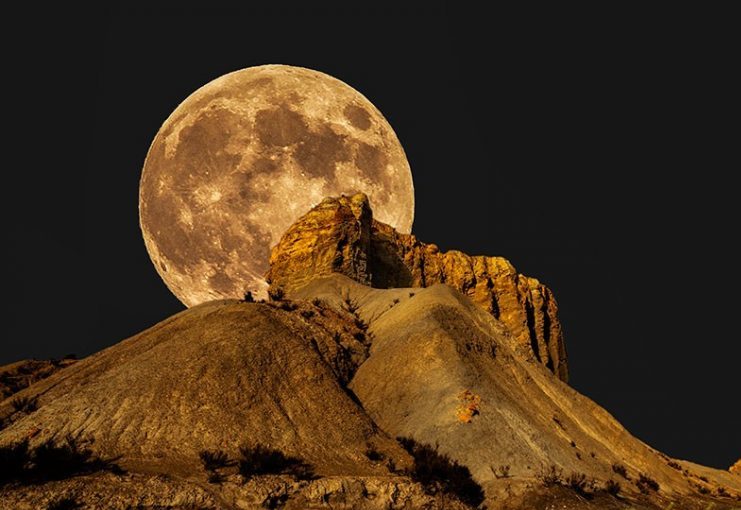 full moon over rock formation in desert