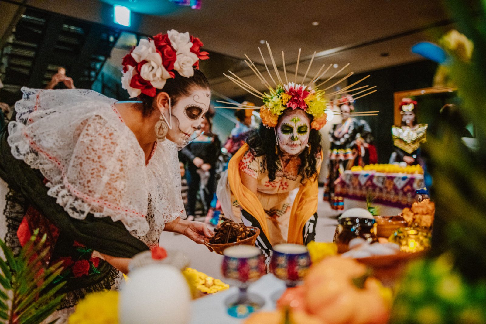 people wearing sugar skull makeup in front of a las ofrendas