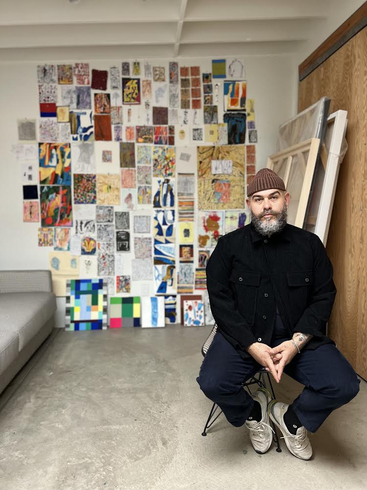 person sitting on a stool with artwork on the wall
